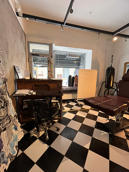 När man går in i lokalen så finns ett stort rum med svart-vitt rutigt golv och vita och grå väggar. Bild.