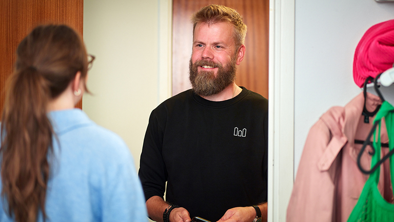 Manlig kvartersvärd står i dörren med en hyresgäst. Foto.